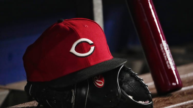 A general view of a Cincinnati Reds cap and glove in the dugout.