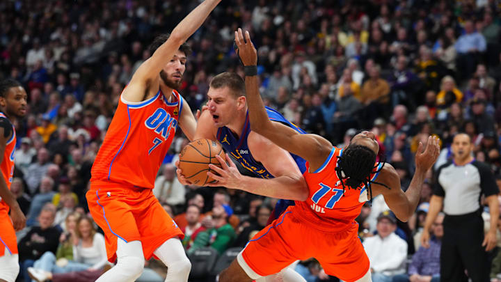 Dec 16, 2023; Denver, Colorado, USA; Denver Nuggets center Nikola Jokic (15) drives against Oklahoma City Thunder guard Isaiah Joe (11) and forward Chet Holmgren (7) in the second half at Ball Arena. Mandatory Credit: Ron Chenoy-Imagn Images