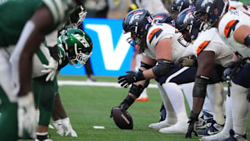 Oct 12, 2025; Tottenham, United Kingdom; Helmets at the line of scrimmage as Denver Broncos center Luke Wattenberg (60) snaps the ball against the New York Jets during an NFL International Series game at Tottenham Hotspur Stadium. Mandatory Credit: Kirby Lee-Imagn Images