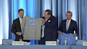 Dec 12, 2024; Chapel Hill, NC, USA;  North Carolina Tar Heels chancellor Lee Roberts presents a cut off sweatshirt to new head coach Bill Belichick with a jersey from athletic director Bubba Cunningham at Loudermilk Center for Excellence. Mandatory Credit: Jim Dedmon-Imagn Images