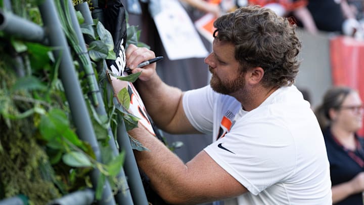 Cincinnati Bengals center Ted Karras (64) signs his autograph for fans before NFL preseason game between the Cincinnati Bengals and the Indianapolis Colts at Paycor Stadium in Cincinnati on Thursday, Aug. 22, 2024.