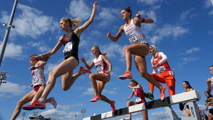 Gracie Hyde of Arkansas (104) races over the water jump in the women's steeplechase during the NCAA West Preliminary in College Station, Texas.