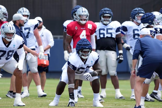 Dallas Cowboys quarterback Dak Prescott prepares to take the snap as guard Tyler Booker reacts at training camp.