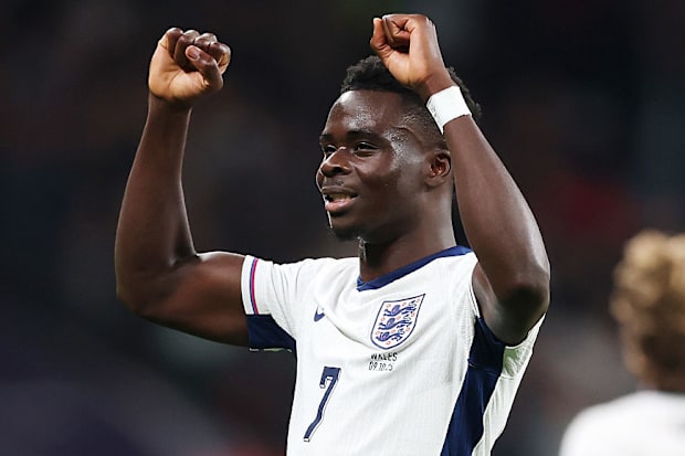Bukayo Saka raising his arms in victory.