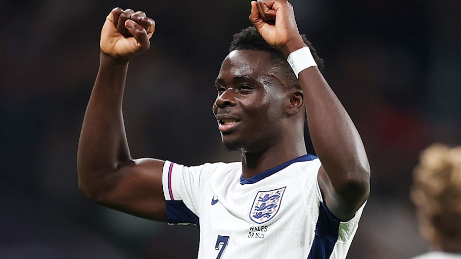 Bukayo Saka raising his arms in victory.