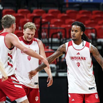 Indiana basketball guard Lamar Wilkerson high-fives teammate Trent Sisley, standing between Tucker DeVries and Ian Stephens.