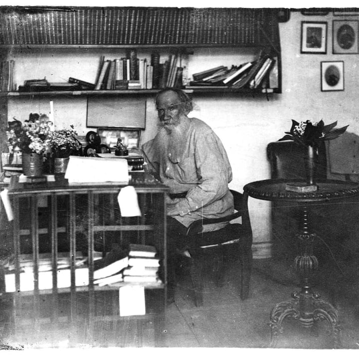 Leo Tolstoy sitting at his desk in his study.