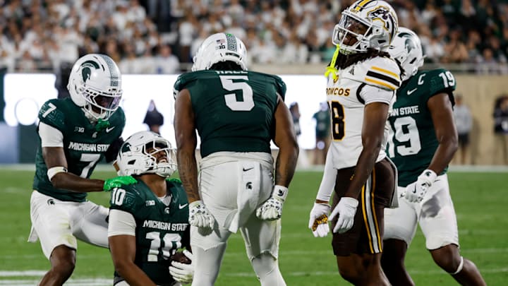 Michigan State's Jordan Hall and Joshua Eaton celebrate with Wayne Matthew III after he makes an interception.