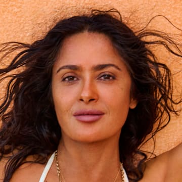 Salma Hayek Pinault was photographed by Ruven Afanador in Mexico. Swimsuit by TJ Swim. Necklace by Foundrae. Body chain by Isa Grutman. Belly chain by Saint Laurent.