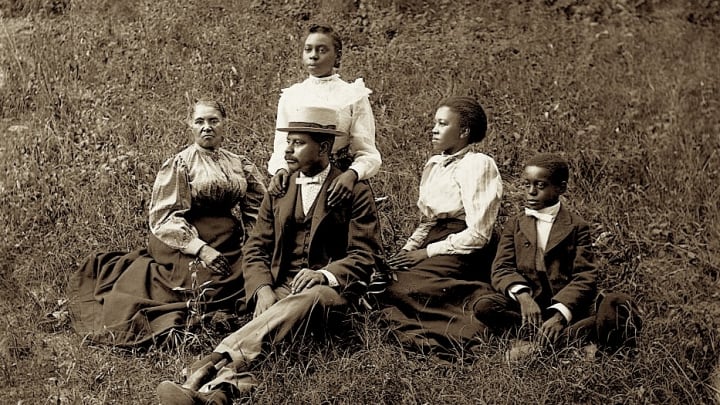 An African American family from Georgia sits together outdoors, circa 1890.