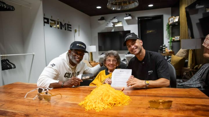 Colorado Buffaloes superfan Peggy Coppom signing her NIL deal with Blenders Eyewear in a collaboration with Deion Sanders.