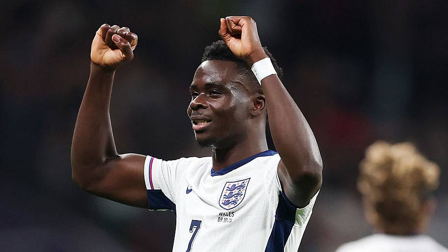 Bukayo Saka raising his arms in victory.