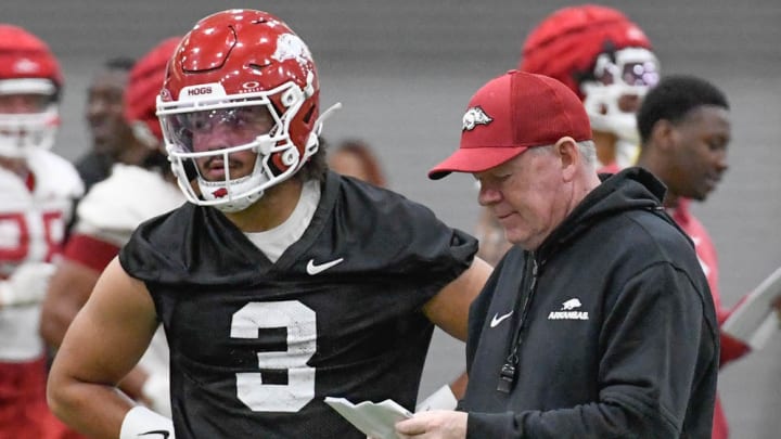 Arkansas Razorbacks offensive coordinator looks over the play sheet while quarterback Malachi Singleton watches the group ahead of him during a spring practice on the indoor practice facilty in Fayetteville, Arkansas.