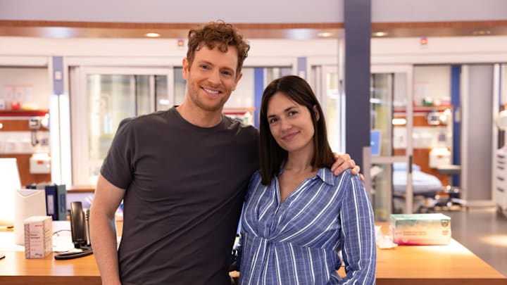Torrey DeVitto and Nick Gehlfuss standing together on the set of Chicago Med