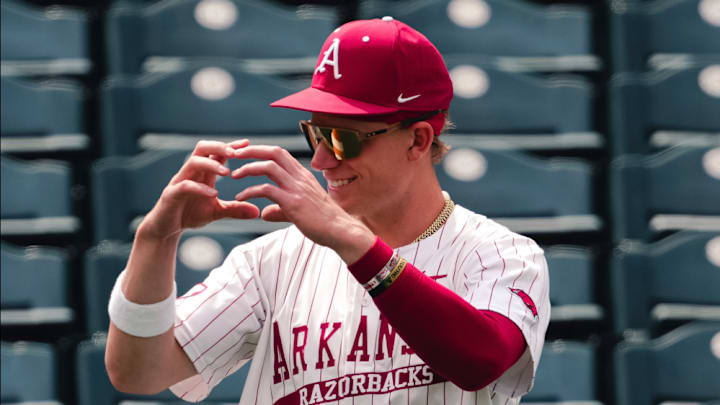 A member of the Arkansas Razorbacks makes a heart shape with his hands on a day where fans can bring dogs to Baum-Walker to watch the Hogs.