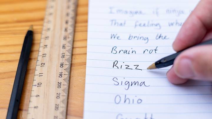 Person writing Gen Z and Gen Alpha slang words on lined paper Person writing Gen Z and Gen Alpha slang words on lined paper