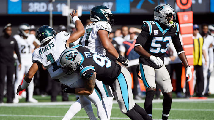 CHARLOTTE, NORTH CAROLINA - OCTOBER 10: Defensive end Morgan Fox #91 of the Carolina Panthers hits quarterback Jalen Hurts #1 of the Philadelphia Eagles during the football game at Bank of America Stadium on October 10, 2021 in Charlotte, North Carolina.