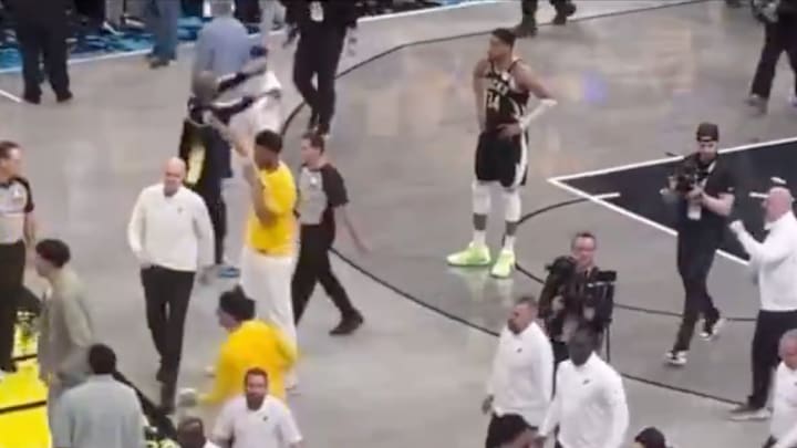 Giannis Antetokounmpo watches Tyrese Haliburton’s father hold up a flag in front of him.