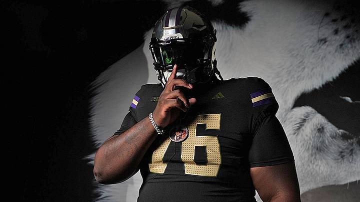 Dajohn Yarborough poses in front of a Husky wall logo on his visit. 