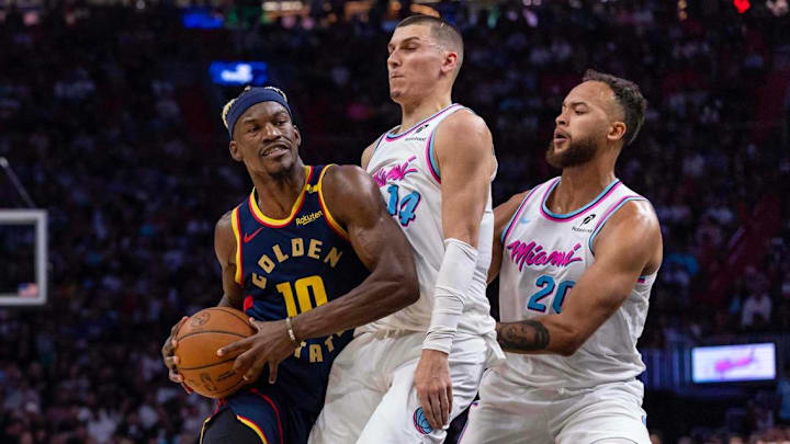 Golden State Warriors forward Jimmy Butler III (10) drives down the lane into the paint while defended by Miami Heat guard Tyler Herro (14) and forward Kyle Anderson (20) during the first half of an NBA game at Kaseya Center on Tuesday, March 25, 2025, in Miami, Florida. 