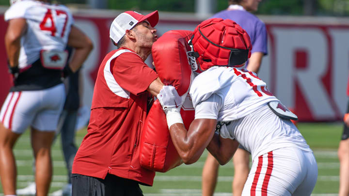 Arkansas Razorbacks wide receivers coach Antonio Jordan delivers a block to wide receivers coach Ronnie Fouch holding blocking shield in fall camp practices on the outdoor fields in Fayetteville, Ark. Arkansas Razorbacks wide receivers coach Antonio Jordan delivers a block to wide receivers coach Ronnie Fouch holding blocking shield in fall camp practices on the outdoor fields in Fayetteville, Ark.