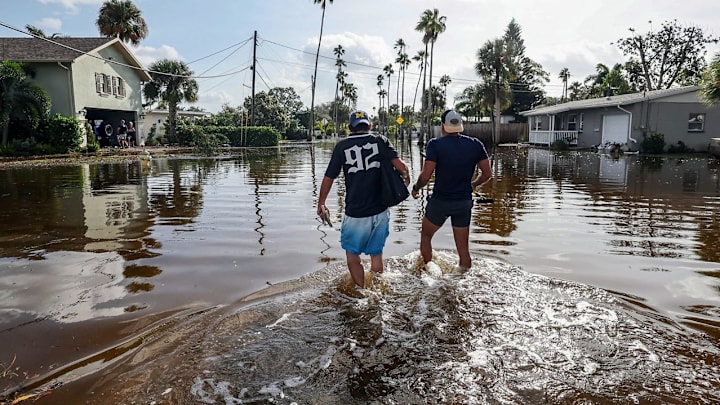 Thomas Chaves, left, and Vinny Almeida walk through floodwaters from Hurricane Helene in an attempt to reach Chaves's mother's house in the Shore Acres neighborhood Friday, Sept. 27, 2024, in St. Petersburg, Fla.