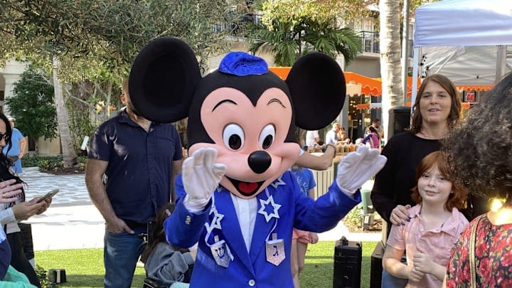 Mickey Mouse, in a Hanukkah-themed suit, dances and poses for photos at The Square in West Palm