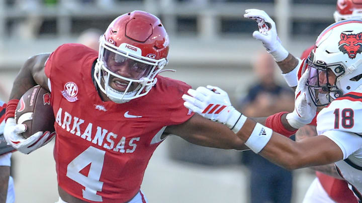 Arkansas Razorbacks running back Mike Washington stiff-arms an Arkansas State Red Wolves defender at War Memorial Stadium in Little Rock, Ark.