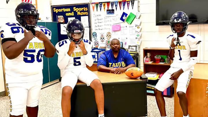 Mount Tabor head football coach Tiesuan Brown (seated) with three of his players who are modeling the team's new white uniforms for the 2024 season.