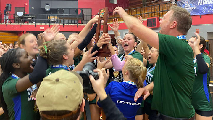 Naples' Seacrest Country Day players and coaches celebrate with the state championship trophy after winning their fourth consecutive state title Wednesday at Polk State College in Winter Haven.