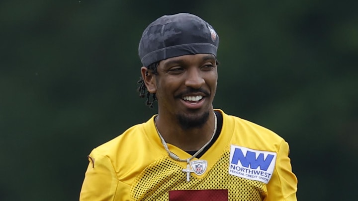 Jun 5, 2024; Ashburn, VA, USA; Washington Commanders quarterback Jayden Daniels (5) smiles on the field during an OTA workout at Commanders Park. Mandatory Credit: Geoff Burke-Imagn Images