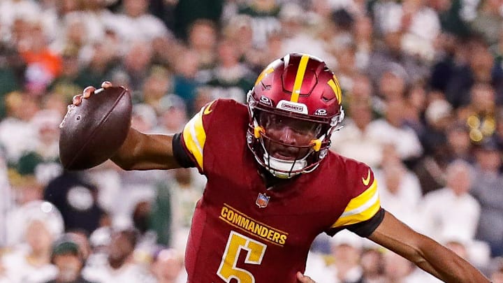 Washington Commanders quarterback Jayden Daniels scrambles away from Green Bay Packers defensive end Lukas Van Ness.