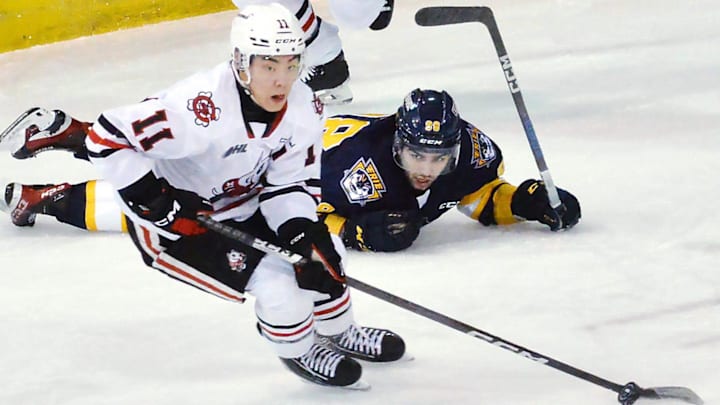 Niagara IceDogs forward Kevin He controls the puck near Erie Otters forward Pano Fimis in the first period of an Ontario Hockey League game at Erie Insurance Arena in Erie on Feb. 14, 2024.