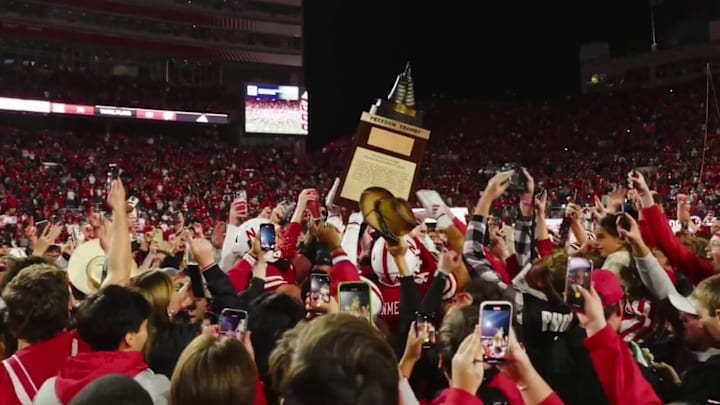 Surrounded by fans on the field, Nebraska players hoist the Freedom Trophy after their game against Wisconsin.
