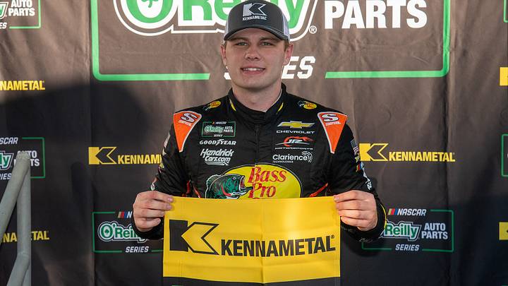 Carson Kvapil poses with the Kennametal Pole Award flag after scoring the pole position for Saturday's National Debt Relief 250 at Martinsville Speedway.
