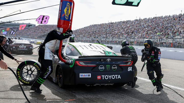 A.J. Rosini (right) running toward the left side of Ty Gibbs' No. 54 Toyota after completing a right-side tire change during the Mobil 1 301 at New Hampshire.