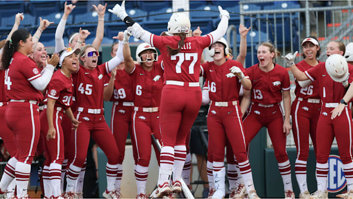 Arkansas softball's Bri Ellis jumps on home plate and celebrates with her teammates after hitting a home run.