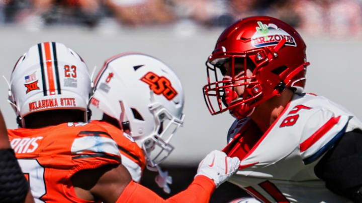 Oct 4, 2025; Tucson, Arizona, USA; Oklahoma State Cowboys safety Kenneth Harris (23) (left, obscured) pulls the jersey of Arizona Wildcats tight end Sam Olson (84) during the second quarter at Arizona Stadium. Mandatory Credit: Aryanna Frank-Imagn Images