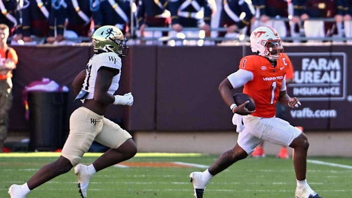 Oct 4, 2025; Blacksburg, Virginia, USA;  Virginia Tech Hokies quarterback Kyron Drones (1) runs toward the sideline with the ball against Wake Forest Demon Deacons linebacker Aiden Hall (21) during the fourth quarter at Lane Stadium. Mandatory Credit: Brian Bishop-Imagn Images