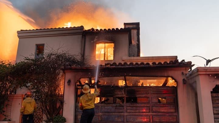 Firefighters attempt to extinguish a fire in a home along the Pacific Coast Highway in the Pacific Palisades neighborhood on Jan. 8, 2025. A wildfire broke out in Los Angeles County on Jan. 7, which has destroyed more than 1,000 homes, businesses and other structures, Los Angeles County Fire Chief Anthony Marrone said at a briefing Wednesday.