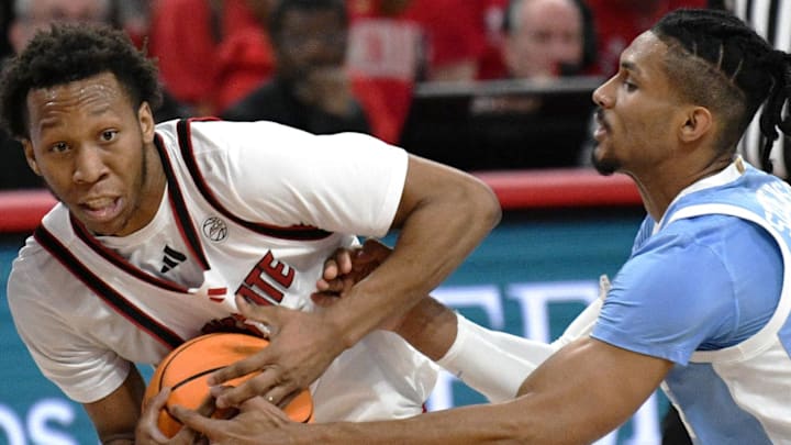 Feb 17, 2026; Raleigh, North Carolina, USA;  NC State Wolfpack guard Quadir Copeland (11) protects the ball against North Carolina Tar Heels forward Jarin Stevenson (15) during the first half at Lenovo Center. Mandatory Credit: Zachary Taft-Imagn Images