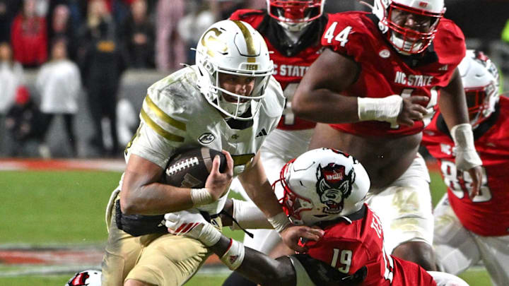 Nov 1, 2025; Raleigh, North Carolina, USA;  North Carolina State Wolfpack saftey Tristan Teasdell (19) attempts to tackle Georgia Tech Yellow Jackets quarterback Haynes King (10) during the fourth quarter at Carter-Finley Stadium. Mandatory Credit: Zachary Taft-Imagn Images