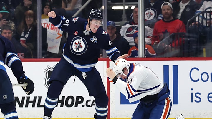 Jan 8, 2026; Winnipeg, Manitoba, CAN; Winnipeg Jets defenseman Logan Stanley (64) fights with Edmonton Oilers center Trent Frederic (10) in the second period at Canada Life Centre. Mandatory Credit: James Carey Lauder-Imagn Images