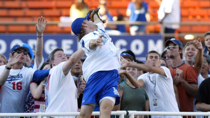 James Van der Beek jumps over the fence to catch a fly ball hit by Rob Lowe during Hollywood Stars Night at Dodger Stadium.