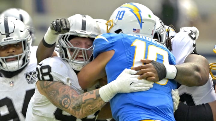 Sep 8, 2024; Inglewood, California, USA; Los Angeles Chargers quarterback Justin Herbert (10) is sacked by Las Vegas Raiders defensive end Maxx Crosby (98) in the first half at SoFi Stadium. Mandatory Credit: Jayne Kamin-Oncea-Imagn Images