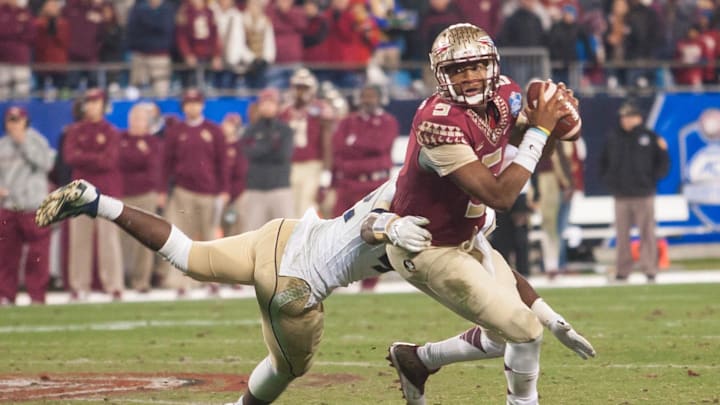 Dec 6, 2014; Charlotte, NC, USA; Florida State Seminoles quarterback Jameis Winston (5) tries to avoid the pressure by Georgia Tech Yellow Jackets defensive end KeShun Freeman (42) during the third quarter at Bank of America Stadium. FSU defeated Georgia Tech 37-35. Mandatory Credit: Jeremy Brevard-Imagn Images