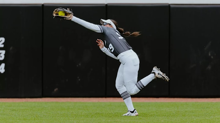 Mizzou softball's Kayley Langer catches a ball in the outfield with an outstretched arm.