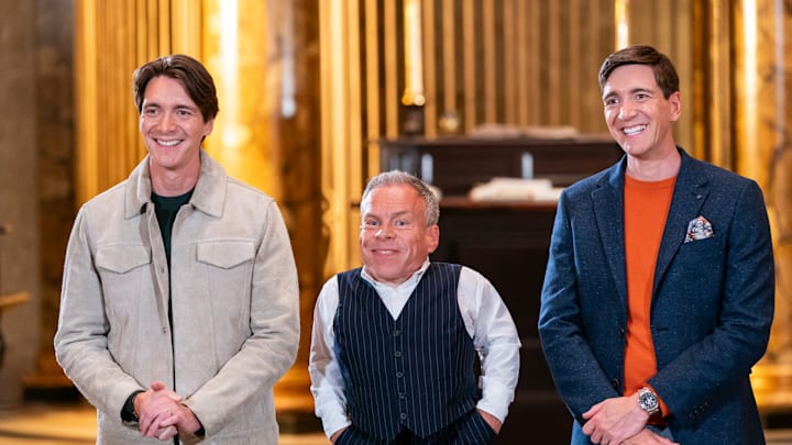 Hosts James Phelps and Oliver Phelps with guest judge Warwick Davis, as seen on Harry Potter: Wizards of Baking, Season 1.