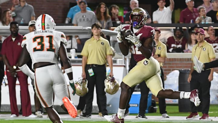 Oct 4, 2025; Tallahassee, Florida, USA; Florida State Seminoles running back Ousmane Kromah (32) makes a catch against Miami Hurricanes linebacker Wesley Bissainthe (31) during the first half at Doak S. Campbell Stadium. Mandatory Credit: Robert Myers-Imagn Images