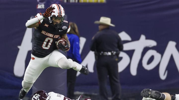 Dec 27, 2023; Houston, TX, USA; Oklahoma State Cowboys running back Ollie Gordon II (0) hurdles Texas A&M Aggies defensive back Dalton Brooks (25) in the second quarter at NRG Stadium. Mandatory Credit: Thomas Shea-USA TODAY Sports Dec 27, 2023; Houston, TX, USA; Oklahoma State Cowboys running back Ollie Gordon II (0) hurdles Texas A&M Aggies defensive back Dalton Brooks (25) in the second quarter at NRG Stadium. Mandatory Credit: Thomas Shea-USA TODAY Sports